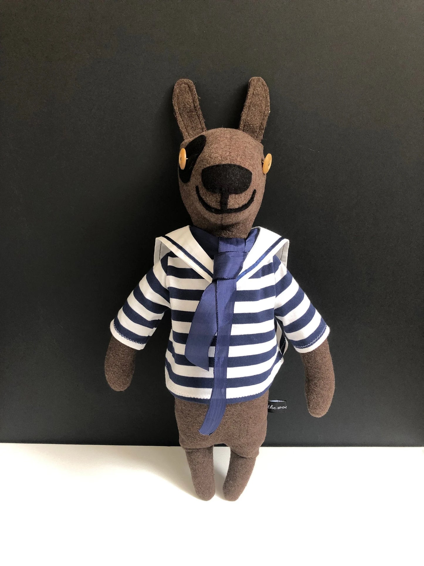 Sailor Sam Woolly Dog
Each woolly dog character I make is one of a kind with their own personality. Sam the sailor has been beautifully handmade with chocolate brown pure new wool and wears a removable blue and white stripe cotton sailor top with collar and blue tie.
Sam is filled with a non-allergenic soft toy filling conforming to BS + CE standards for hygiene + fire safety, which makes him firm and able to stand propped against a wall as a lovely nursery decoration.
NOT SUITABLE FOR CHILDREN UNDER 3