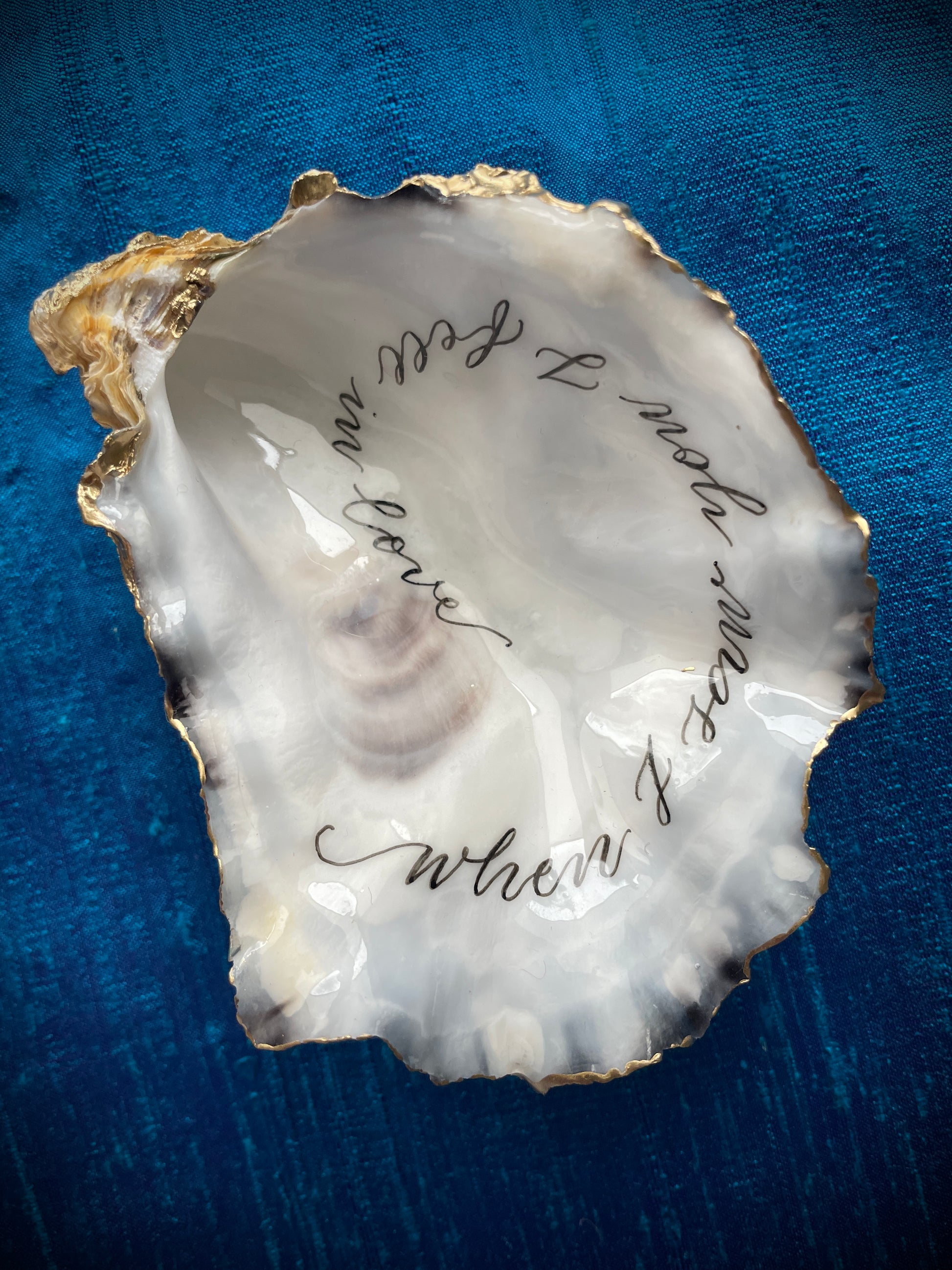 Cornish Oyster Shell Calligraphy
Made by: Julia Brooke - a word in your shell
'When I saw you I fell in love'
The inside of this Cornish oyster shell has been beautifully hand written with a romantic message, delicately edged with gold leaf and the back lightly burnished with gold wax... perfect as a romantic gift.
The inside has been protected with clear uv stable resin making it moisture resistant, but not suitable for aquatic display.
Size approx: 9.5 cm x 8 cm / 3+3/4" x 3+1/4"