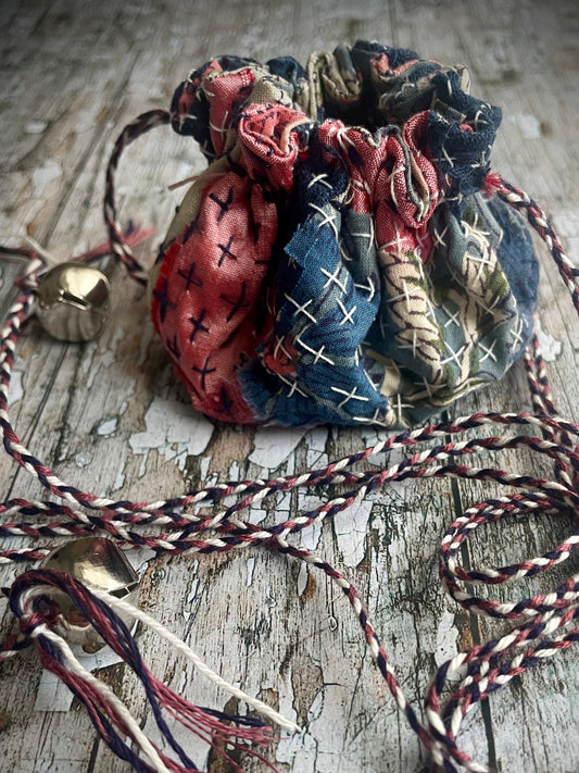 Small hand Stitched Sashiko + Boro Pouch
Beautiful Sashiko stitched drawstring textile pouch to hold your precious memories a photograph, crystals, or beach finds. Made by hand stitching on vintage Japanese dark indigo blue linen, vintage velvet, silk and cotton, lined with a pretty floral cotton. I then plaited 3 colours of matching cotton thread to make the drawstring cords ending in small silver colour bells.
Pouch diameter when open approximately: 7+1/2" / 19 cm.
Cord lengths approximately: 20" / 51 cm