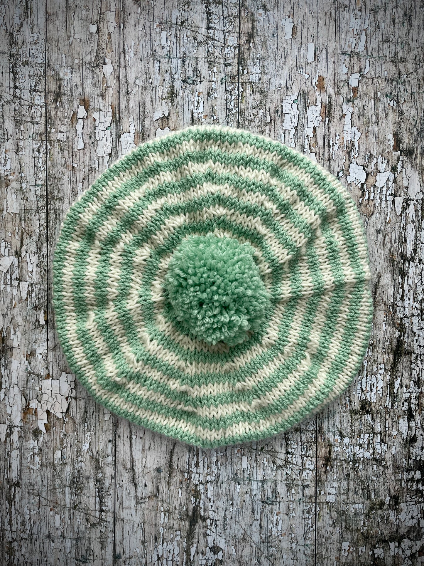 CHILDREN'S PISTACHIO + CREAM STRIPED WOOL BERET
Beautifully hand knitted beret in soft pure wool and merino wool, perfect for keeping little heads warm on cold days. Knitted in nautical Breton stripes of pistachio green and cream, with a big green pom and green ribbed band that gives the hat a snug fit. It would look lovely on boys or girls.

SIZE: child 6 - 24 mths.
Diameter approximately: 26cm / 10+1/4".
CARE: hand wash or machine wash on wool cycle at 30 degrees, dry flat, do not tumble dry.