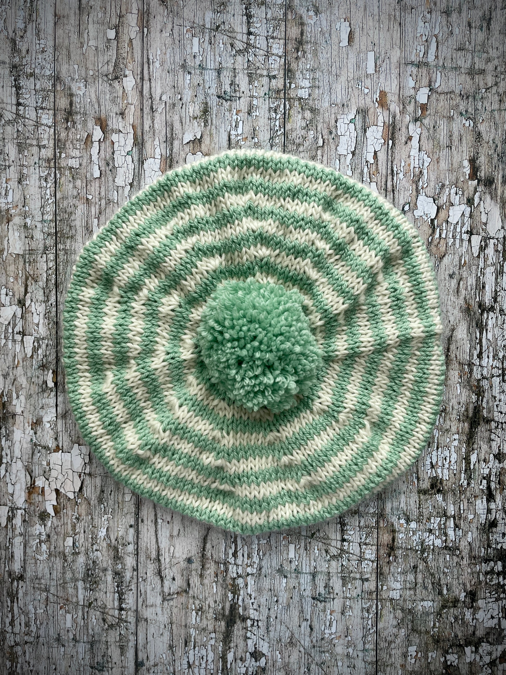 CHILDREN'S PISTACHIO + CREAM STRIPED WOOL BERET
Beautifully hand knitted beret in soft pure wool and merino wool, perfect for keeping little heads warm on cold days. Knitted in nautical Breton stripes of pistachio green and cream, with a big green pom and green ribbed band that gives the hat a snug fit. It would look lovely on boys or girls.

SIZE: child 6 - 24 mths.
Diameter approximately: 26cm / 10+1/4".
CARE: hand wash or machine wash on wool cycle at 30 degrees, dry flat, do not tumble dry.