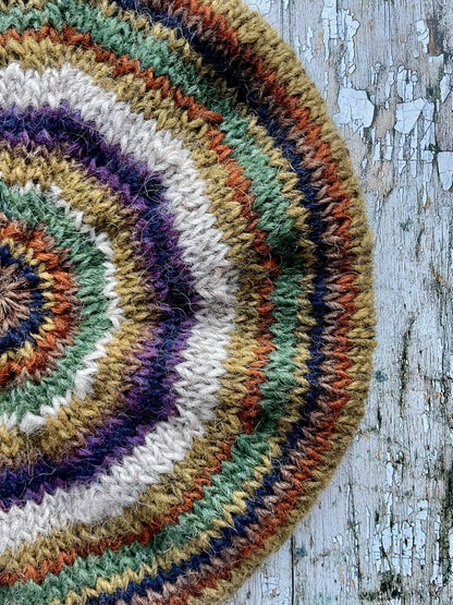 Beautifully hand knitted beret in Icelandic wool, perfect for keeping your head warm on cold days and adding a touch of 40's style to any outfit. Knitted in oat, sage green heather, dark kelp, violet heather, navy, burnt orange and milk chocolate stripes, with a green heather ribbed band that gives the hat a snug fit.

SIZE: adult.

CARE: hand wash or machine wash on wool cycle at 30 degrees, dry flat, do not tumble dry.