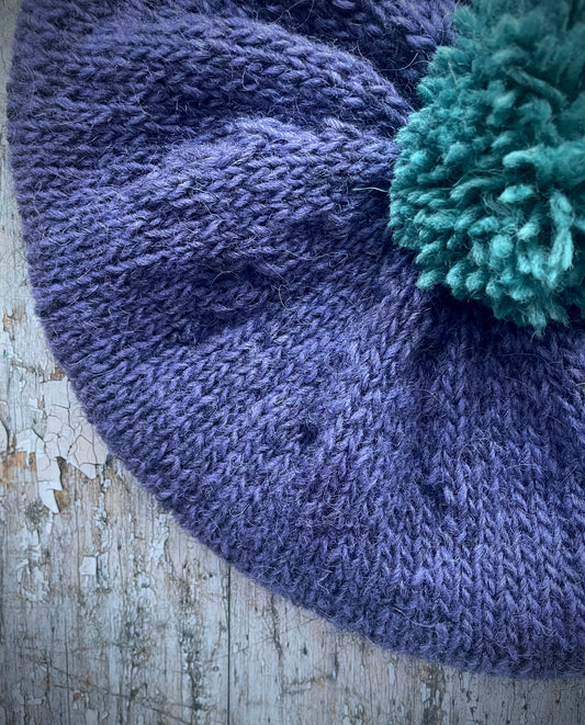 Hand Knitted Wool Lavender + Viridian Beret

Beautifully hand knitted beret in Icelandic pure wool, perfect for keeping your head warm on cold days. Knitted in a deep lavender, with a big viridian pom and a ribbed band that gives the hat a snug fit.

SIZE: adult.

CARE: hand wash or machine wash on wool cycle at 30 degrees, dry flat, do not tumble dry.
