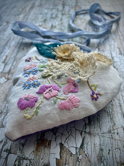 A beautiful one of a kind heart... made by hand stitching together vintage embroidered linen of pink, mauve, lavender and blue flowers, with vintage cream lace, linen flowers and a blue velvet leaf embellished with small silver bugle beads. The back is made of pale lavender velvet and the heart hangs with a loop of blue raw edged sari silk to wear around the neck or hang on the wall as a decoration. The inside of the heart has been gently filled with non-allergenic filling conforming to BS + CE  standards.