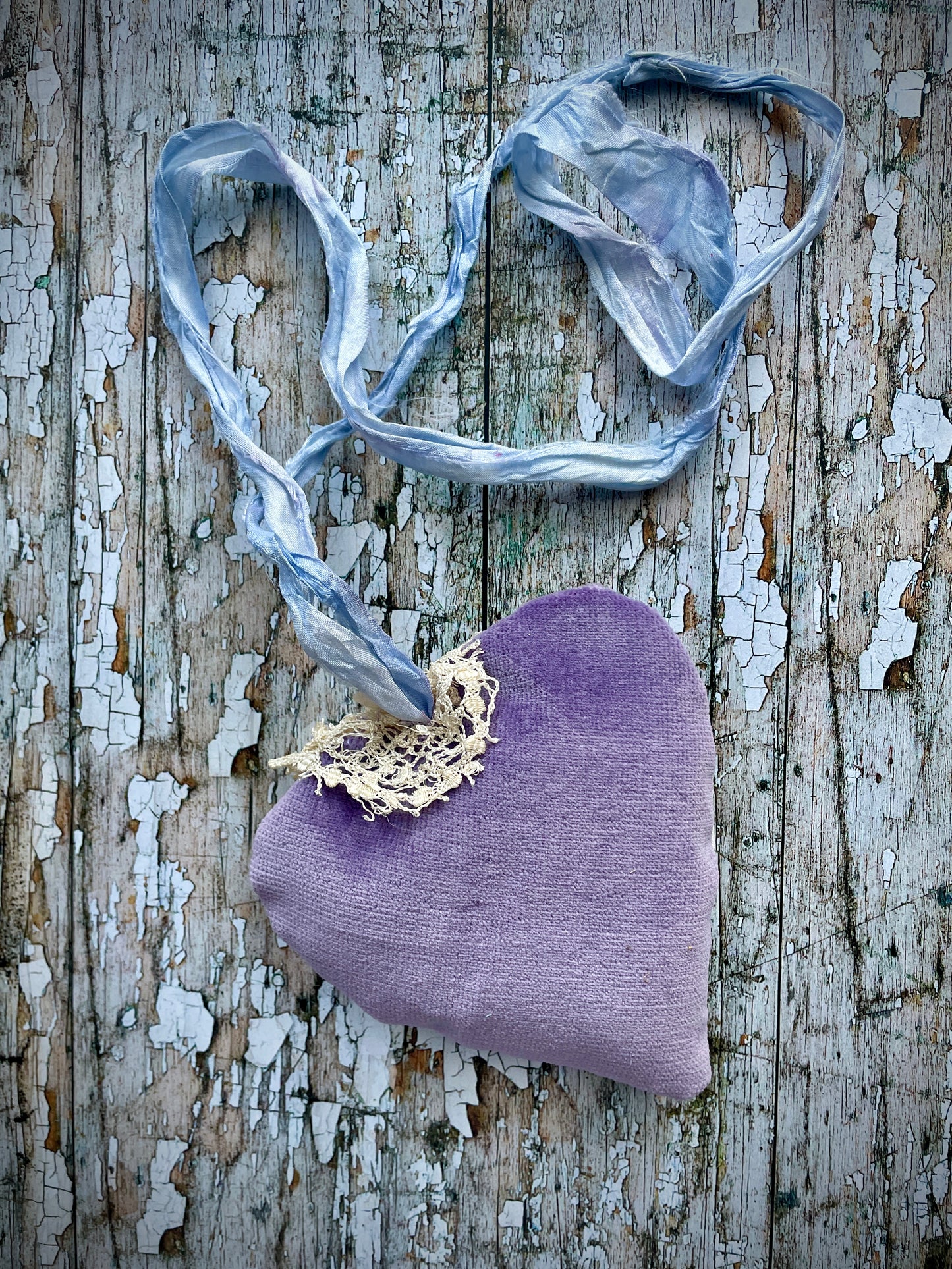 A beautiful one of a kind heart... made by hand stitching together vintage embroidered linen of pink, mauve, lavender and blue flowers, with vintage cream lace, linen flowers and a blue velvet leaf embellished with small silver bugle beads. The back is made of pale lavender velvet and the heart hangs with a loop of blue raw edged sari silk to wear around the neck or hang on the wall as a decoration. The inside of the heart has been gently filled with non-allergenic filling conforming to BS + CE  standards.