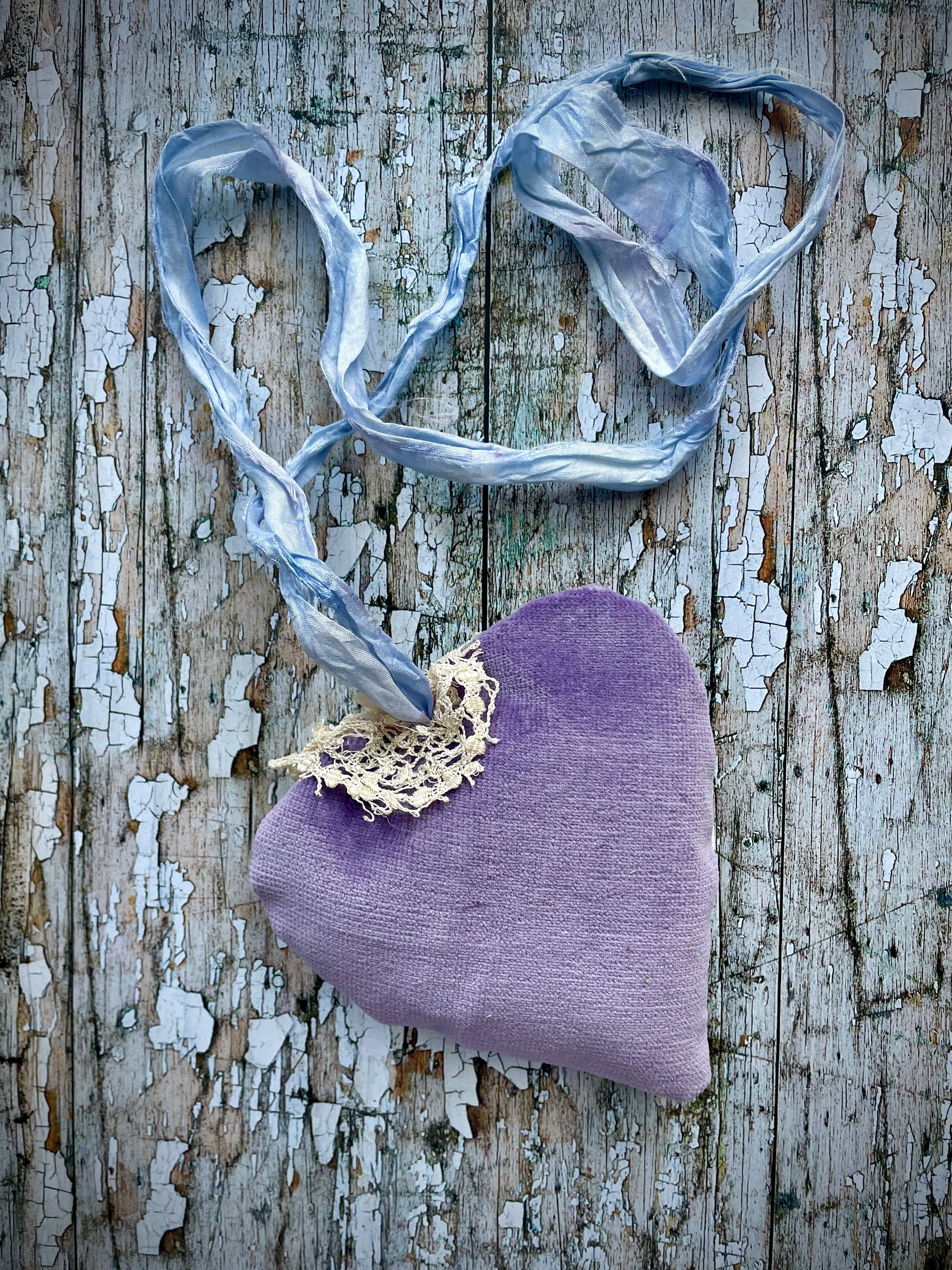 A beautiful one of a kind heart... made by hand stitching together vintage embroidered linen of pink, mauve, lavender and blue flowers, with vintage cream lace, linen flowers and a blue velvet leaf embellished with small silver bugle beads. The back is made of pale lavender velvet and the heart hangs with a loop of blue raw edged sari silk to wear around the neck or hang on the wall as a decoration. The inside of the heart has been gently filled with non-allergenic filling conforming to BS + CE  standards.
